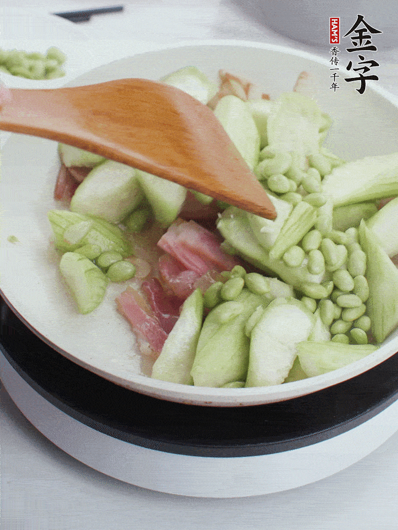 依次下絲瓜、青豆翻炒，炒至絲瓜打蔫縮小。